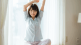 朝日を浴びながらストレッチする30代女性の目覚めのセルフケア